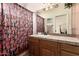 Bathroom with vibrant wallpaper and tile counters with a large mirror at 5534 W Riviera Dr, Glendale, AZ 85304