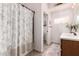 Bathroom showcasing a shower with a floral curtain, an elegant vanity, and a well-lit space at 5534 W Riviera Dr, Glendale, AZ 85304