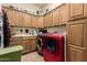 Well-organized laundry room featuring wooden cabinets, countertops, and a red front-load washer and dryer set at 5534 W Riviera Dr, Glendale, AZ 85304