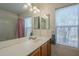 Spacious bathroom featuring a dual sink vanity, shower with patterned curtain, and window with blinds at 5919 W Blackhawk Dr, Glendale, AZ 85308