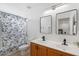 Clean bathroom with double sinks, wood cabinets, modern fixtures, and a shower with a stylish blue and white curtain at 7027 W Midway Ave, Glendale, AZ 85303