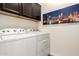 Laundry room with side by side washer and dryer below dark cabinets, and a modern art print at 820 E Constance Way, Phoenix, AZ 85042