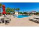 Community pool with lounge chairs, tables with umbrellas, palm trees, and several chairs available at 820 E Constance Way, Phoenix, AZ 85042