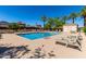 Community pool with several tables and lounge chairs surrounded by palm trees, greenery, and umbrellas at 820 E Constance Way, Phoenix, AZ 85042