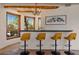 Stylish bar area features four stools, granite countertop, and windows with views of the lush outdoor landscaping at 8306 E Buckskin Trl, Scottsdale, AZ 85255