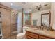 Well-lit bathroom with stone countertops, a large mirror, and glass-enclosed shower at 8306 E Buckskin Trl, Scottsdale, AZ 85255