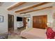 Spacious bedroom featuring wood ceiling beams, stone floors, and a private bathroom at 8306 E Buckskin Trl, Scottsdale, AZ 85255