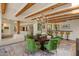 Dining room featuring a round table, green upholstered chairs, exposed beam ceilings, and stone floors at 8306 E Buckskin Trl, Scottsdale, AZ 85255