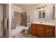 Bathroom with neutral tile shower and wood vanity with tile countertop at 9011 N 52Nd Ave, Glendale, AZ 85302