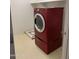 Bright laundry room featuring a modern, red front-load washer and storage shelf at 9018 W Superior Ave, Tolleson, AZ 85353