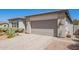 Exterior angle view of the home's 2-car garage, desert landscaping, and block facade at 10240 E Supernova Dr, Mesa, AZ 85212