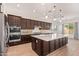 Spacious kitchen featuring dark wood cabinetry, a large center island, and stainless steel appliances at 10240 E Supernova Dr, Mesa, AZ 85212