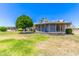 Lush backyard with green grass, mature trees, and a screened-in patio under a clear blue sky at 10651 W Saratoga Cir, Sun City, AZ 85351