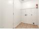 Functional laundry room with tiled floor, storage shelf and washer/dryer hookups at 16264 W Pioneer St, Goodyear, AZ 85338
