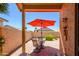Covered patio view of a backyard featuring desert landscaping, a dining set, and a vibrant red umbrella at 17449 N Fairway Dr, Surprise, AZ 85374