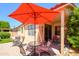 Covered backyard patio featuring an outdoor dining area with a vibrant red umbrella at 17449 N Fairway Dr, Surprise, AZ 85374