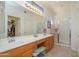 Well-lit bathroom with a double sink vanity, a large mirror, and a walk-in shower at 17449 N Fairway Dr, Surprise, AZ 85374