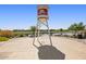 A vintage water tower next to a scenic pond with blooming flowers and lush greenery at 23038 E Twilight Dr, Queen Creek, AZ 85142