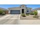 Charming single-story home featuring a gray garage door, stone accents, and well-maintained desert landscaping at 35816 W San Ildefanso Ave, Maricopa, AZ 85138