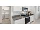 Well-lit kitchen showcases stainless steel range, microwave, granite counters, and white cabinets at 35816 W San Ildefanso Ave, Maricopa, AZ 85138