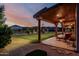 Serene backyard featuring a covered patio, manicured lawn, and desert sunset views at 3718 N Briere Ct, Buckeye, AZ 85396
