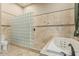Bright bathroom with spa tub, large glass blocked shower, and travertine tile at 3718 N Briere Ct, Buckeye, AZ 85396