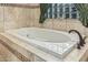 Spa-like bath with large tub surrounded by travertine tile, shower, and natural light at 3718 N Briere Ct, Buckeye, AZ 85396