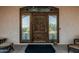 Elegant wood front door with glass panels, decorative wreath, and covered entryway at 3718 N Briere Ct, Buckeye, AZ 85396