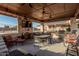 Outdoor kitchen with bar seating, dining area, and grill, all under a covered structure at 3718 N Briere Ct, Buckeye, AZ 85396