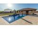 Backyard featuring a sparkling pool, a covered outdoor kitchen, and a beautifully landscaped yard at 3718 N Briere Ct, Buckeye, AZ 85396