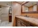 Bathroom vanity with granite counter, dark wood cabinets, decorative mirror, and shower in view at 4856 E Cheryl Dr, Paradise Valley, AZ 85253