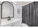 Neutral bathroom features a dark framed mirror and patterned shower curtain at 5101 W Purdue Ave, Glendale, AZ 85302
