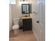 Compact bathroom featuring a toilet, vanity with a granite countertop, and a dark wood cabinet at 5102 W Whispering Wind Dr, Glendale, AZ 85310