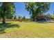 Large, grassy backyard with mature trees and various structures at 5127 W Dobbins Rd, Laveen, AZ 85339