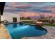Beautiful backyard featuring pool with lit fire features and adjacent outdoor kitchen at 6401 E Larkspur Dr, Scottsdale, AZ 85254