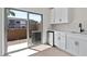 Close-up of the modern wet bar area with white cabinets and mini-fridge, next to sliding glass doors at 7448 S 75Th Ln, Laveen, AZ 85339