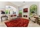 Bright living room with a fireplace, neutral furniture, arched windows, and red rug offers a cozy space at 8216 E Angel Spirit Dr, Scottsdale, AZ 85255
