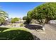 Manicured backyard with artificial grass, decorative rocks, trimmed trees, and a charming rock fountain at 922 S Ember Cir, Mesa, AZ 85208