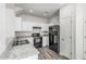 This kitchen offers all white cabinets, black appliances, granite countertops, and wood-look flooring at 923 E Agua Fria Ln, Avondale, AZ 85323