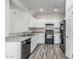This kitchen offers all white cabinets, black appliances, granite countertops, and wood-look flooring at 923 E Agua Fria Ln, Avondale, AZ 85323