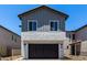 Two-story home featuring grey siding, a stucco base, dark garage door, and minimal desert landscaping at 9408 E Sequence Ave, Mesa, AZ 85212