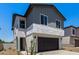 Two-story home featuring grey siding, stucco base, dark garage door, minimal desert landscaping, and a green door at 9408 E Sequence Ave, Mesa, AZ 85212