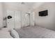 A well-lit bedroom with neutral walls and carpet, including a TV and closet with mirrored doors at 9412 S 34Th Dr, Laveen, AZ 85339