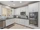Modern kitchen features white cabinets, stainless steel appliances, mosaic backsplash, and ample counter space at 9412 S 34Th Dr, Laveen, AZ 85339