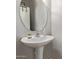 A modern powder room with a pedestal sink, round mirror and decorative accents at 9412 S 34Th Dr, Laveen, AZ 85339