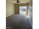 Carpeted room with neutral walls, ceiling fan, and sliding glass door to backyard at 1010 N Osprey Ct, Gilbert, AZ 85234