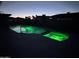An inviting in-ground pool illuminated with green underwater lighting at dusk at 1010 N Osprey Ct, Gilbert, AZ 85234