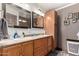A bathroom with a double sink vanity, two mirrors, a tower cabinet, and grey accent walls at 10211 W Hazelwood Ave, Phoenix, AZ 85037