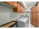 Spacious laundry room with wooden cabinets, white washer and dryer and view into dining area at 1036 N Sierra Hermosa Dr, Litchfield Park, AZ 85340