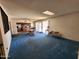 Expansive living area featuring blue carpeting, a ceiling fan, and an open layout connecting to the kitchen at 11216 N 52Nd Ave, Glendale, AZ 85304